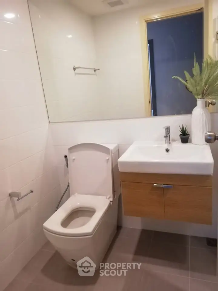 Modern bathroom with sleek fixtures and minimalist design, featuring a wall-mounted sink and contemporary toilet.