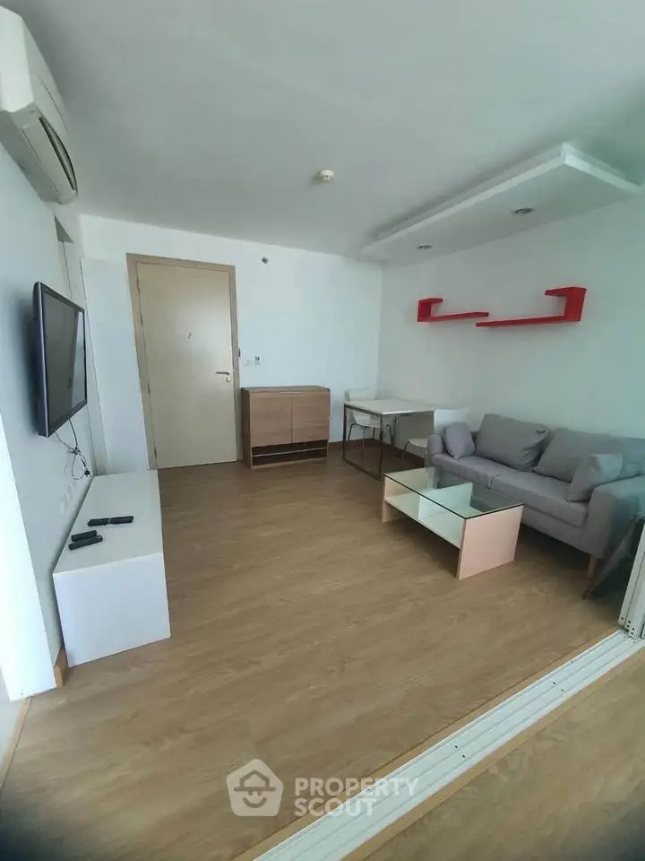 Modern living room with sleek furniture and wooden flooring, featuring a wall-mounted TV and stylish shelving.