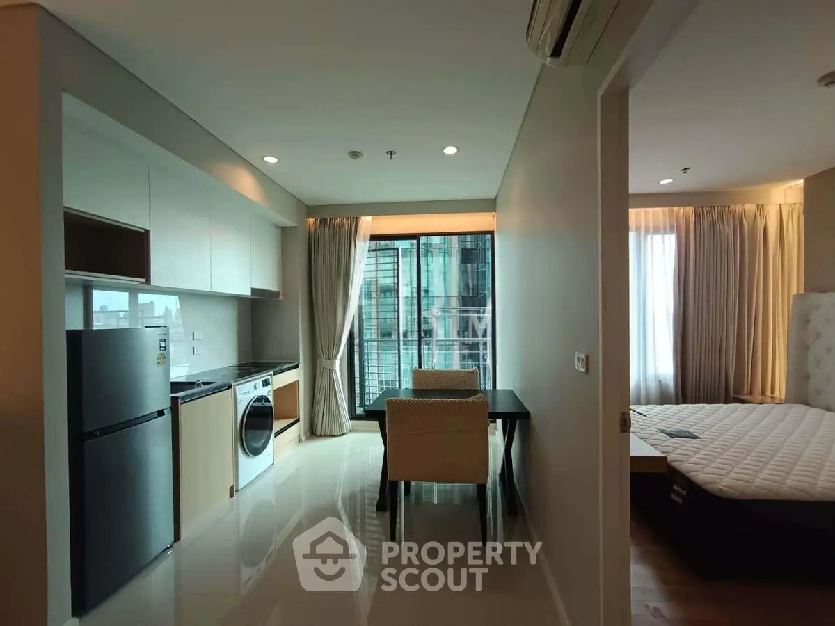 Modern apartment interior with open kitchen and cozy bedroom, featuring sleek appliances and stylish decor.