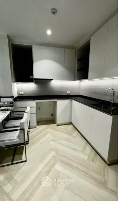 Modern kitchen with sleek cabinetry and stylish herringbone flooring