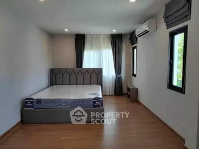 Spacious bedroom with modern decor and large windows for natural light