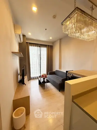 Modern living room with elegant chandelier and cozy sofa in a stylish apartment.