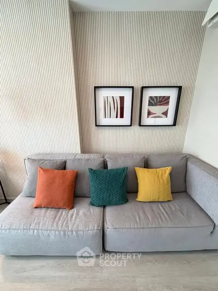 Modern living room with stylish gray sofa and colorful cushions, featuring elegant wall art.