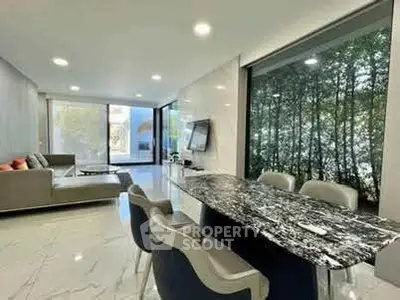 Luxurious modern living room with marble dining table and large windows overlooking greenery.