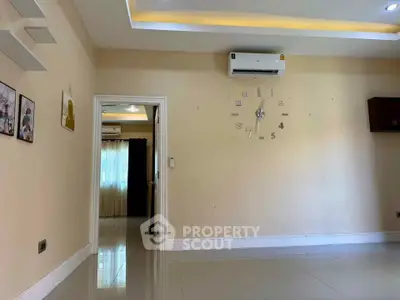 Spacious living room with modern wall clock and air conditioning unit, featuring elegant ceiling lighting.