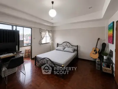 Spacious bedroom with natural light, wooden flooring, and modern decor, perfect for relaxation and comfort.
