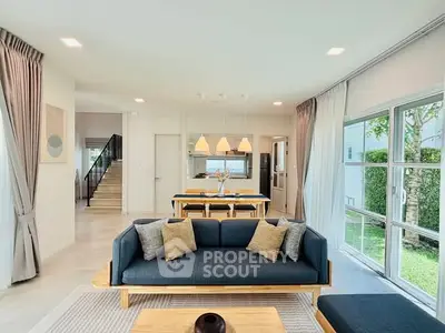 Spacious modern living room with open layout and garden view, featuring elegant decor and ample natural light.