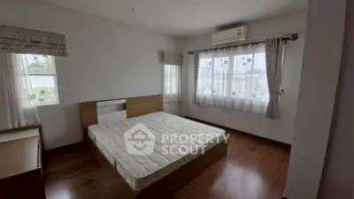 Spacious bedroom with large windows and wooden flooring, featuring a comfortable bed and air conditioning.