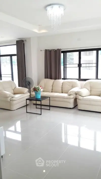 Spacious living room with elegant white sofas and large windows offering natural light.
