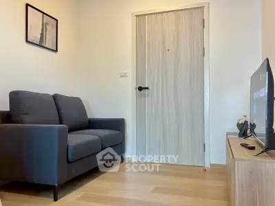 Cozy living room with modern sofa and flat-screen TV, perfect for relaxation.