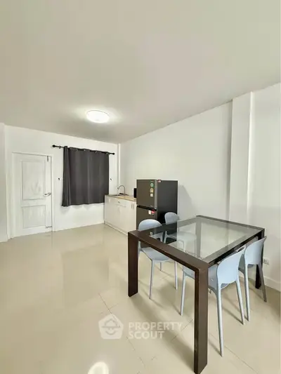 Modern minimalist kitchen with glass dining table and sleek appliances