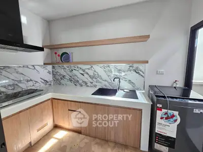 Modern kitchen with marble backsplash and sleek appliances in a stylish apartment.