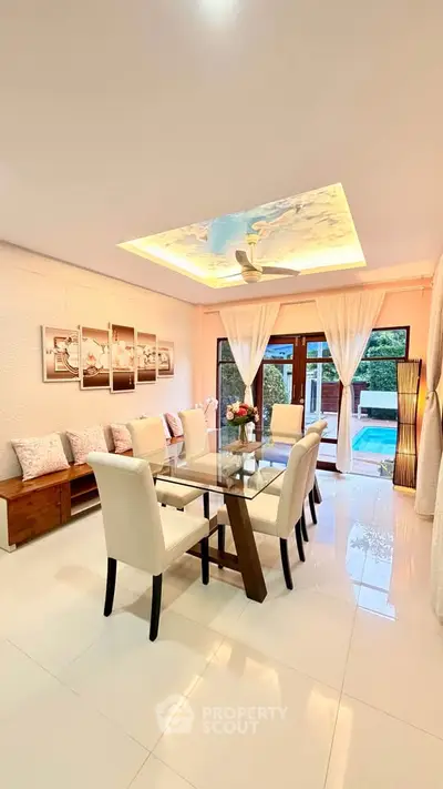 Elegant dining room with glass table, plush chairs, and artistic ceiling lighting, offering a serene ambiance.