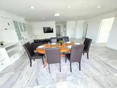 Spacious modern dining area with elegant furniture and sleek flooring in a bright open-plan layout.