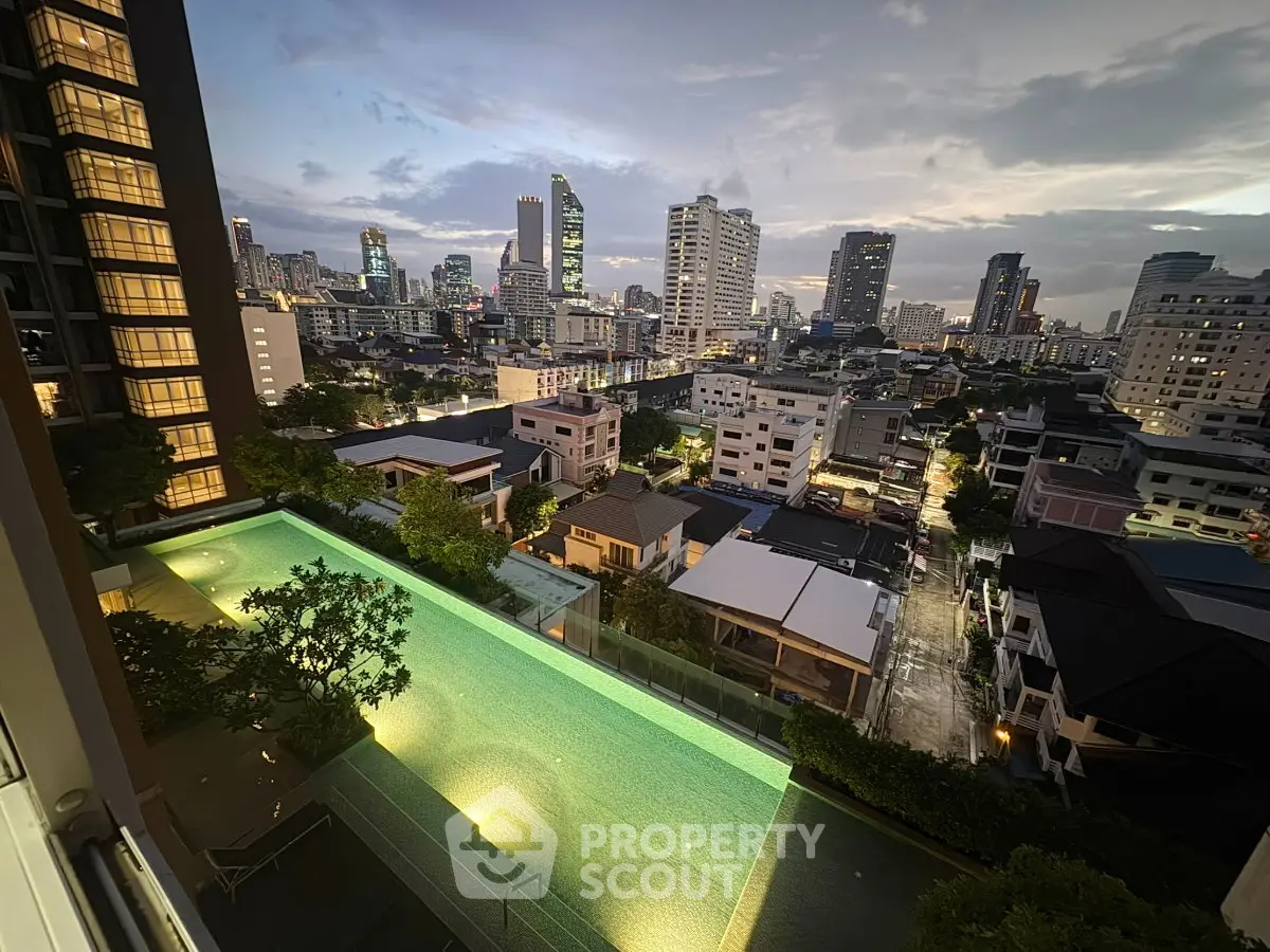 Stunning cityscape view from a high-rise apartment with illuminated pool and skyline at dusk.
