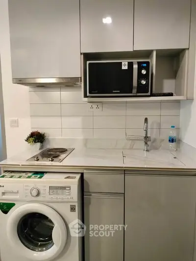 Modern compact kitchen with washing machine and microwave in sleek design.