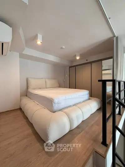 Modern bedroom with stylish bed and sleek wardrobe in a cozy loft space.