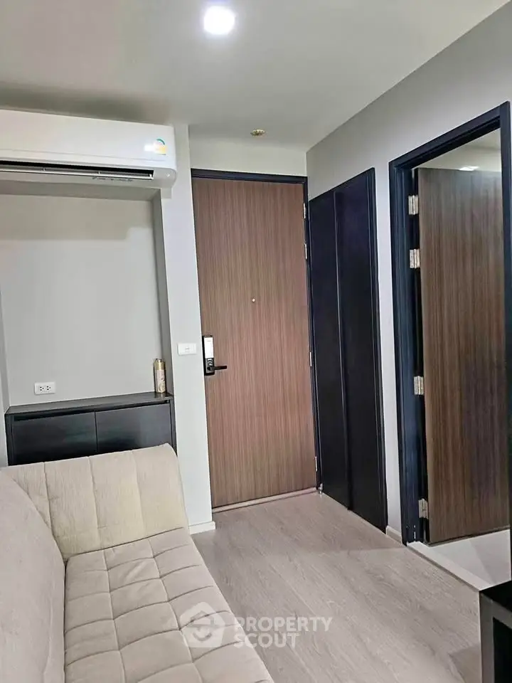 Modern apartment interior with sleek design and neutral tones, featuring a cozy sofa and stylish wooden door.