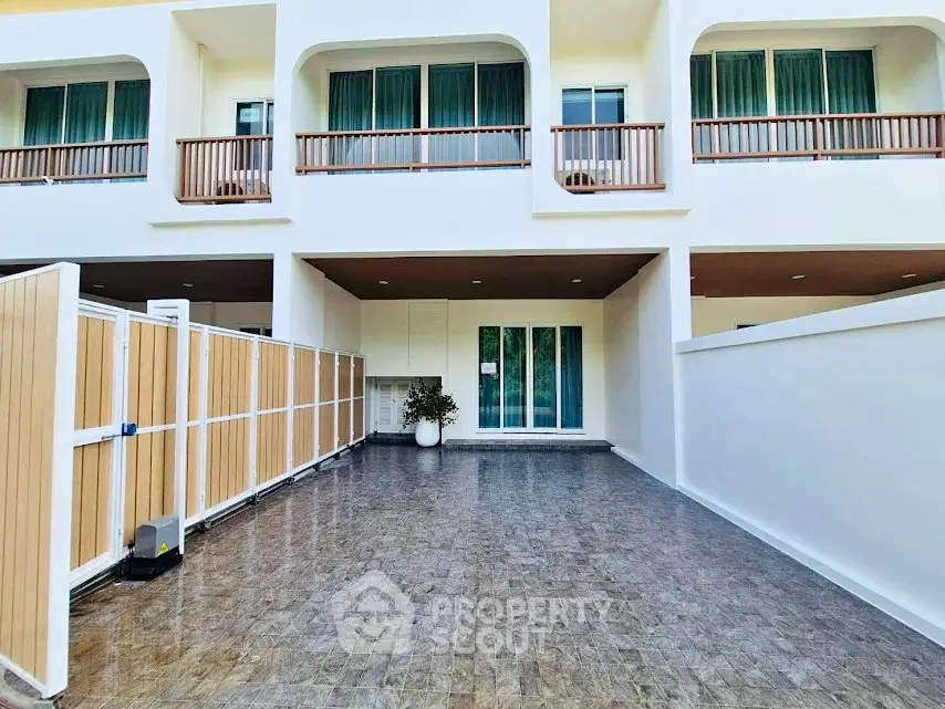 Modern townhouse exterior with spacious tiled patio and elegant balcony design.