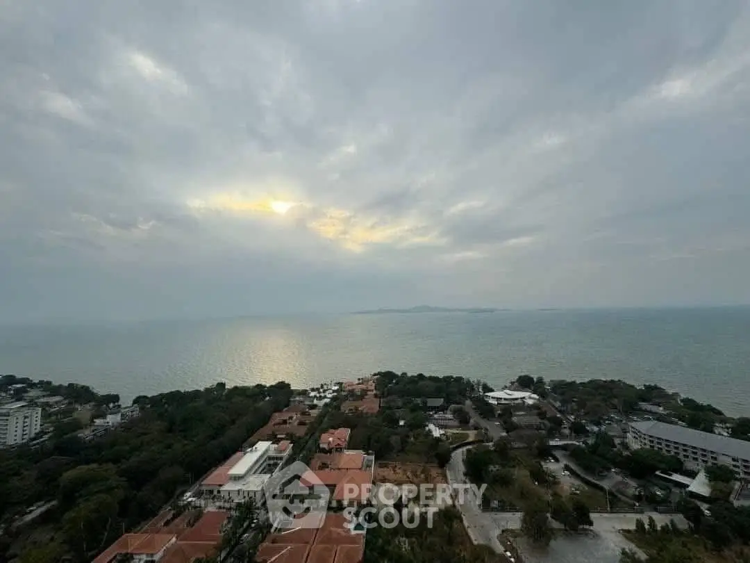Stunning ocean view from high-rise overlooking coastal residential area at sunset.