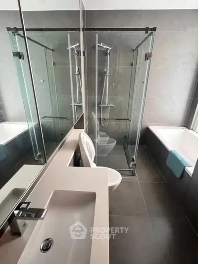 Modern bathroom with glass shower and bathtub in sleek contemporary design.