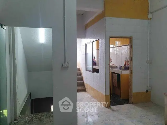 Spacious interior with tiled floors and open layout, featuring a staircase and kitchen area.