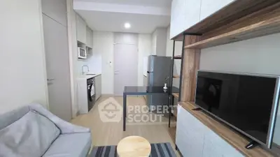 Modern living room with open kitchen, featuring sleek appliances and stylish furniture.