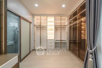 Luxurious walk-in closet with elegant glass doors and ample storage space.