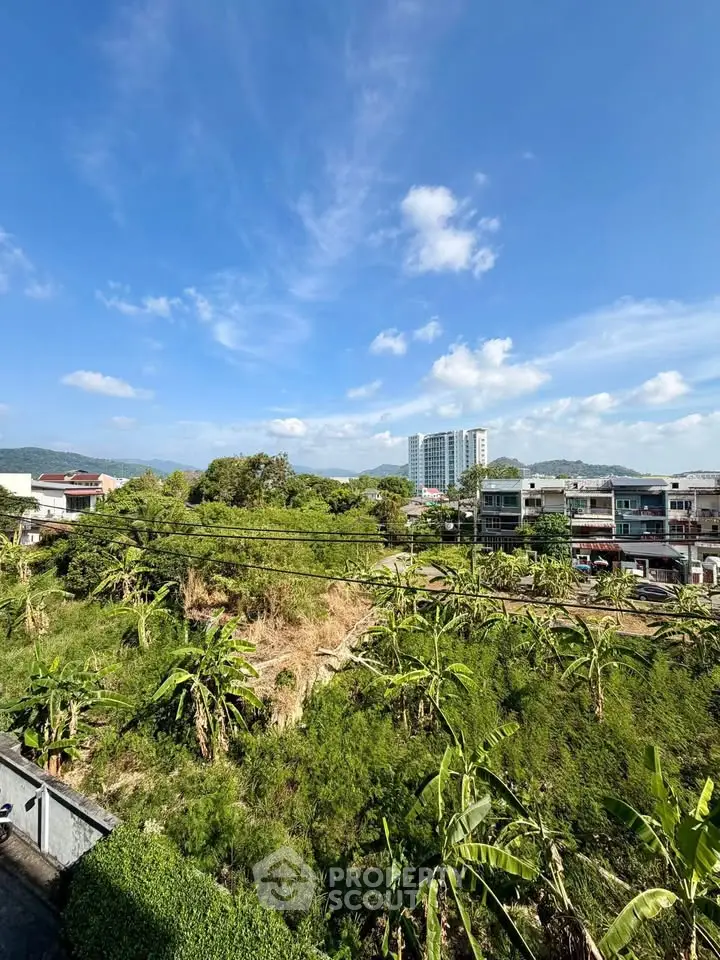 Scenic view of lush greenery and residential buildings under a clear blue sky, perfect for serene living.