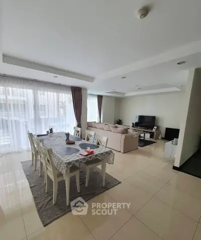 Spacious living room with dining area, modern decor, and natural light