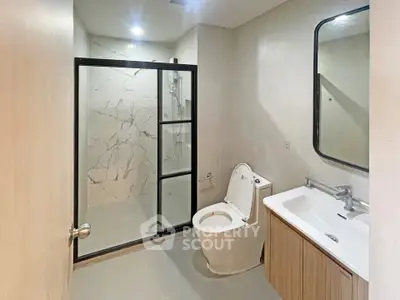 Modern bathroom with glass shower and sleek fixtures in a contemporary apartment.