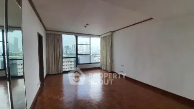Spacious empty living room with large window offering city skyline view, perfect for customization.