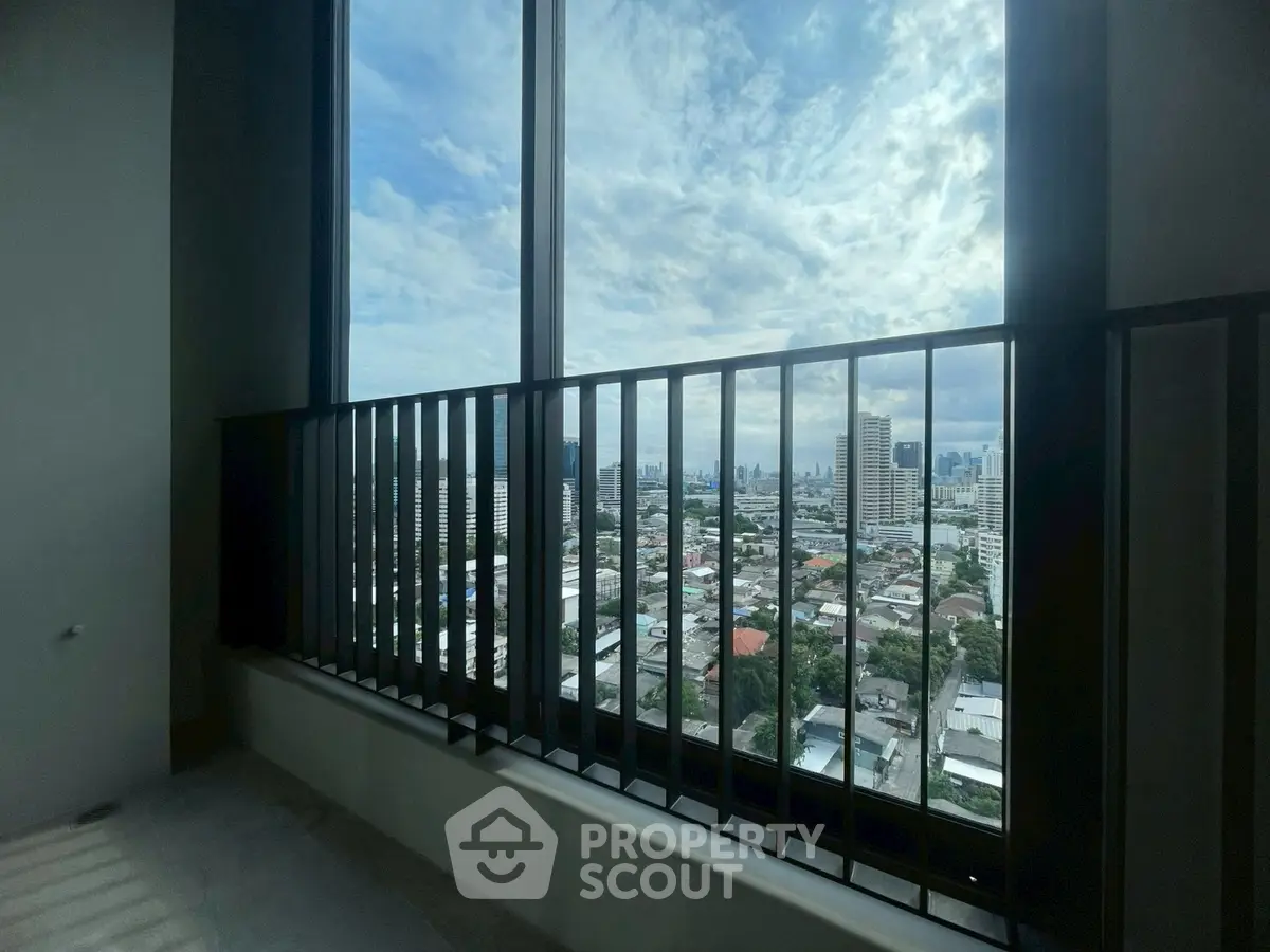 Stunning cityscape view from high-rise apartment balcony with expansive windows.