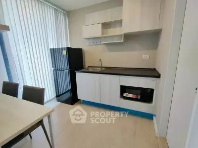 Modern kitchen with sleek cabinetry and dining area in a stylish apartment.