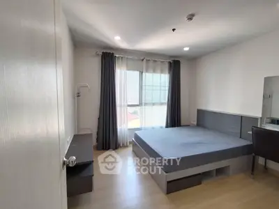 Spacious bedroom with modern furnishings and large window offering natural light.