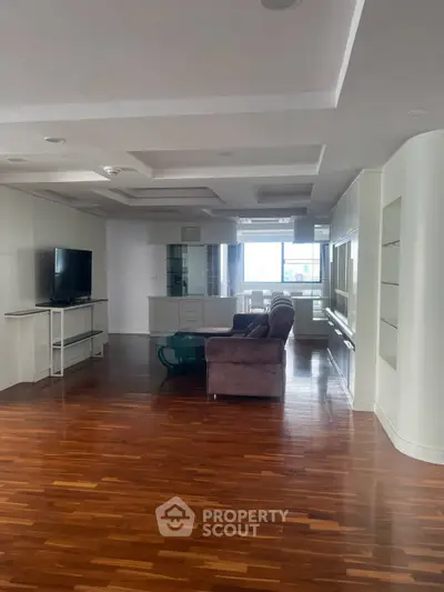Spacious living room with hardwood floors and modern furniture in a bright apartment.