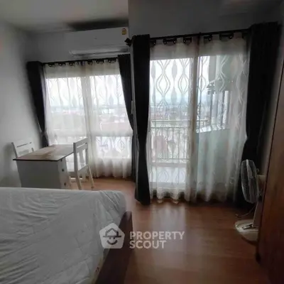 Cozy bedroom with large windows and balcony offering a stunning view, perfect for relaxation.