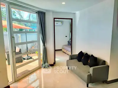 Bright living area with modern sofa and access to outdoor patio, perfect for relaxation.