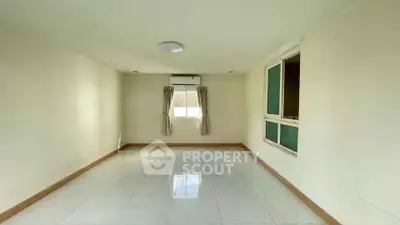 Spacious empty room with large window and air conditioning, perfect for customization.