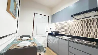 Modern kitchen with sleek cabinetry and stylish backsplash in cozy apartment.