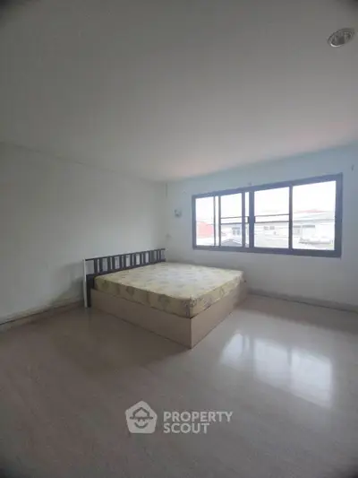 Spacious bedroom with large window and simple decor, perfect for natural light lovers.