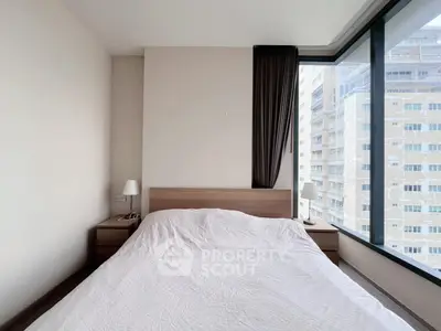 Modern bedroom with large windows offering city views, featuring a cozy bed and minimalist decor.