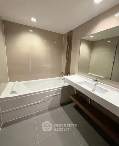 Modern bathroom with sleek bathtub and large mirror in elegant design.