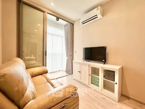 Cozy living room with leather sofa and TV, featuring sliding glass doors and air conditioning.