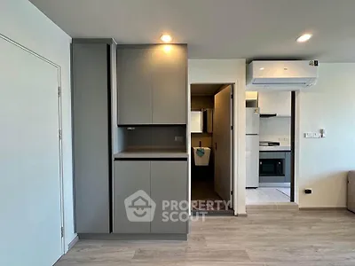 Modern apartment interior with sleek kitchen and air conditioning unit, featuring minimalist design and neutral tones.