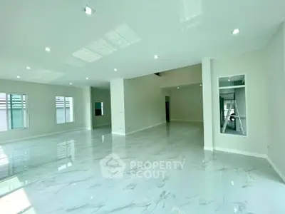 Spacious open-plan living area with glossy marble floors and ample natural light.