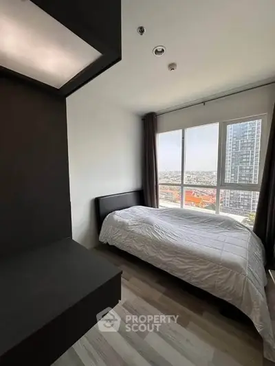 Modern bedroom with large window offering stunning city views in a high-rise apartment.