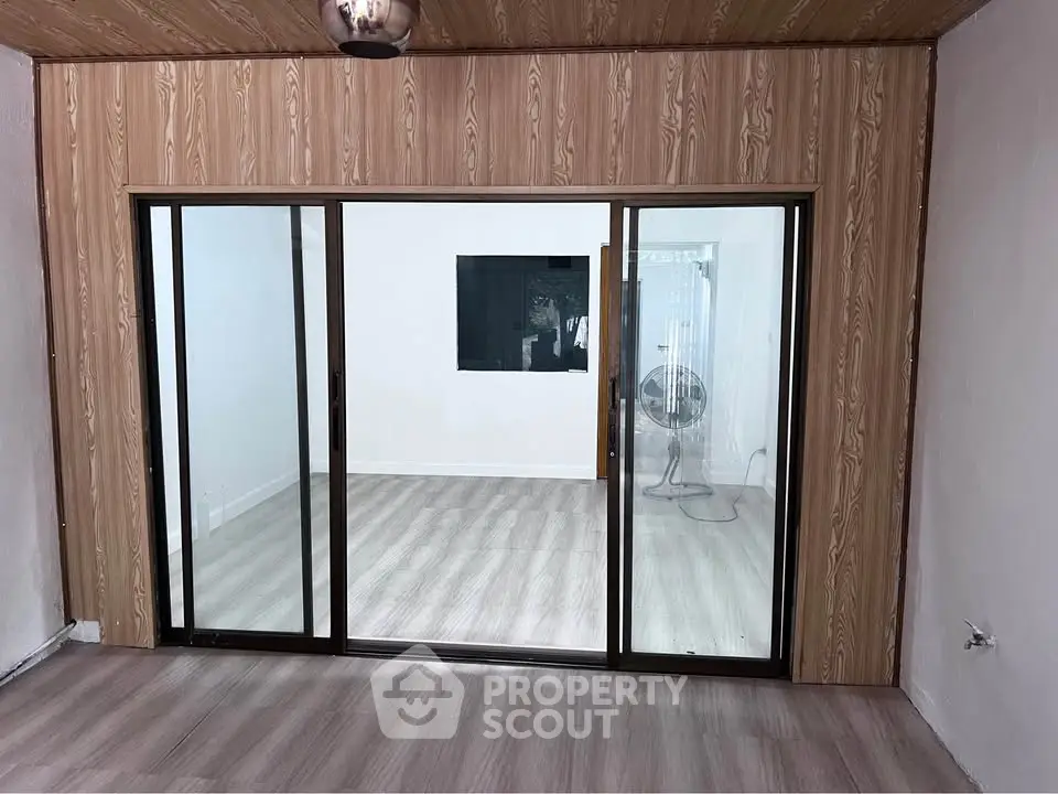 Spacious room with sliding glass doors and wood paneling, ideal for modern living.