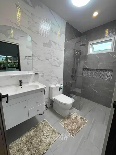 Modern bathroom with sleek design, featuring a glass shower and elegant fixtures.