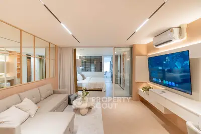 Modern living room with sleek design, large TV, and cozy seating leading to a stylish bedroom.